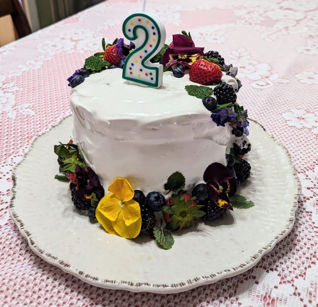 Marshmallow frosting on a gluten free cake with fruit and flowers