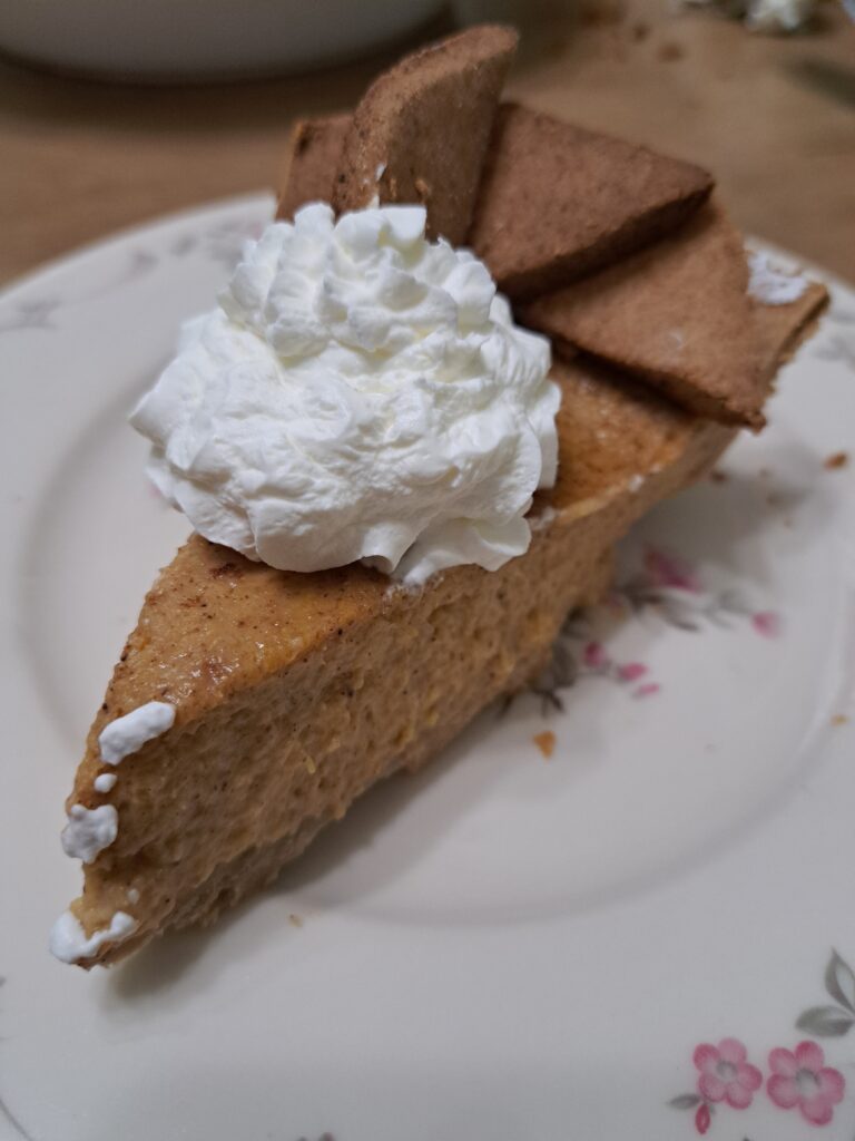 A slice of gluten free pumpkin pie with whipped cream on top